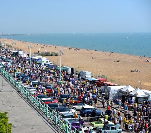 car show on boardwalk next to beach 