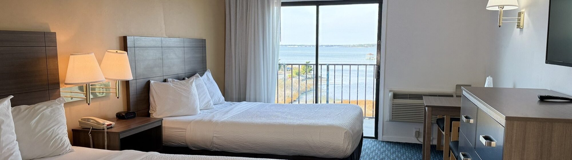 2 clean white beds and a beautiful ocean view outside the window